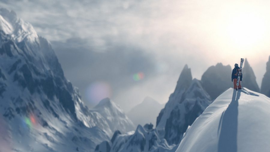 Muž se snowboardem stojící na vrcholu zasněženého kopce ve Steepu