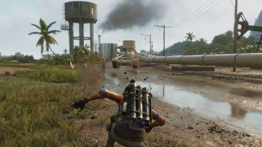 Die Spielerfigur Dani Rojas kauert sich nieder, um ein Mörserfeuer der Exterminador abzufeuern, einer überragenden Waffe in Far Cry 6. Ihr Ziel ist ein Panzer, der sich am Horizont zwischen einer Burg, einer Wasser- und einer Ölpipeline drohend nähert.