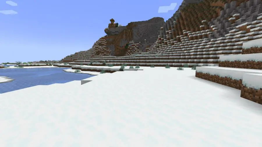 Une région de toundra enneigée avec des collines et un lac gelé, l'un des nombreux biomes Minecraft