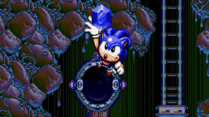 Sonic, en su encarnación de Spinball, llega a la pantalla después de saltar de un agujero, sosteniendo una Chaos Emerald.
