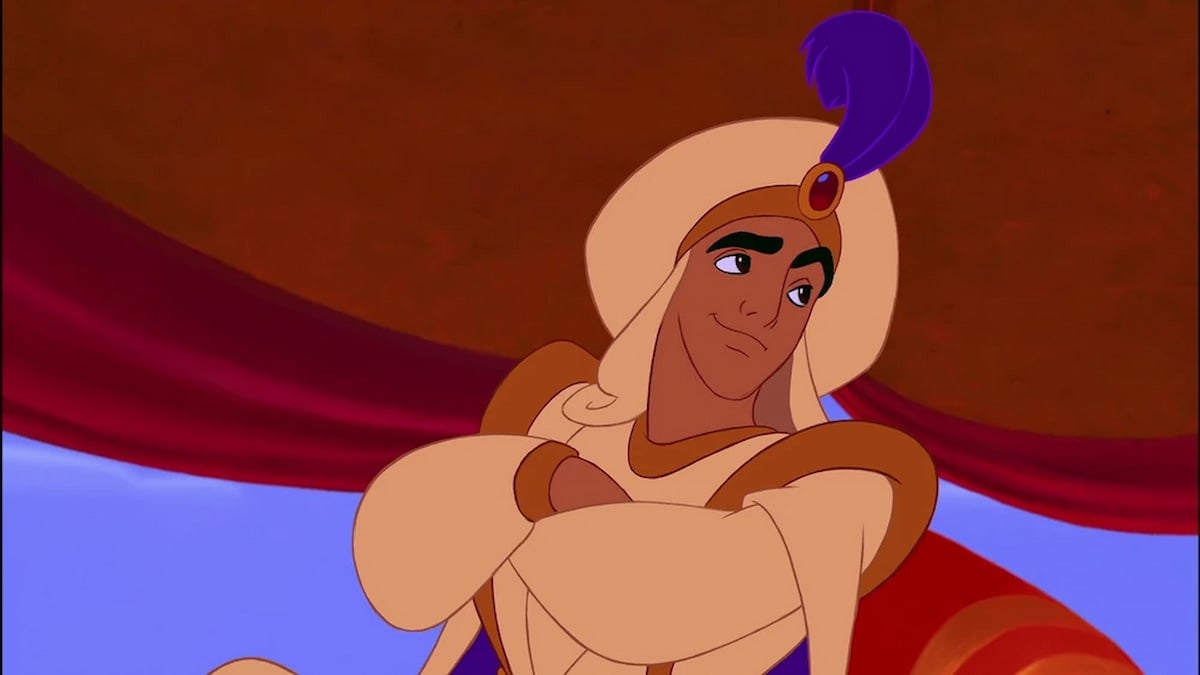 Aladdin en traje de sultán con los brazos cruzados