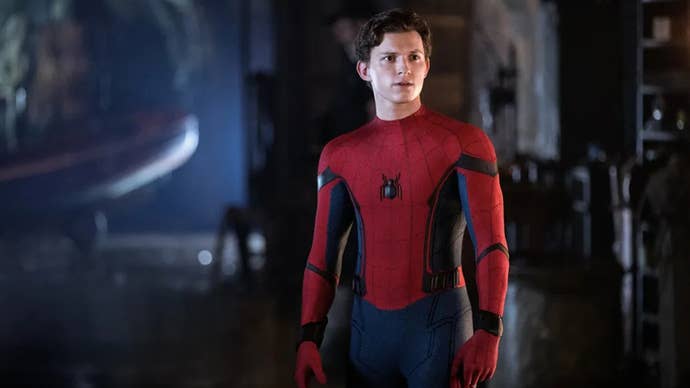 Tom Holland, como Spider-Man, estaba parado en un área con poca luz, vestido con su traje de araña, sin máscara, mirando algo fuera de la pantalla.