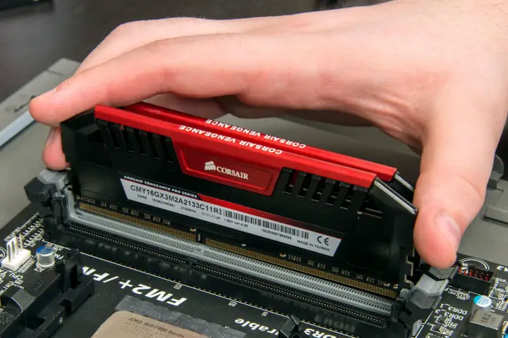 Eine Hand, die ein Corsair-RAM-Modul in ein Desktop-Motherboard einsetzt.
